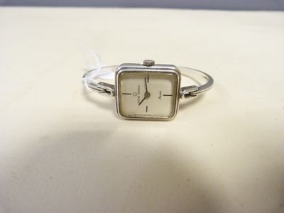 une image représentant une montre argentée au cadran blanc posée sur une surface blanche
