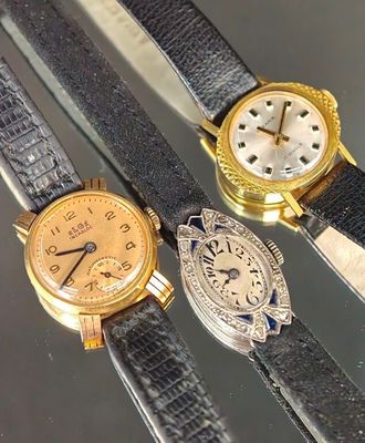Trois types de montres différents sont exposés sur une table en verre