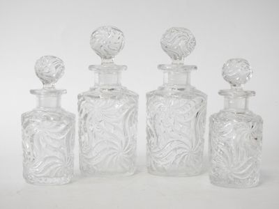 four clear glass bottles with decorative designs are lined up on a white surface