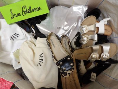 de nombreuses paires de chaussures dans un sac sur lequel est accrochée une étiquette avec un nom