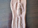 une photo d'une figurine en argile représentant une personne, posée sur une table en bois