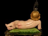 a figurine of a baby laying on a green cushion
