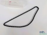 a black and white beaded necklace on a white table