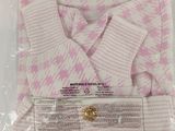 a pink and white sweater in a plastic bag on a white surface