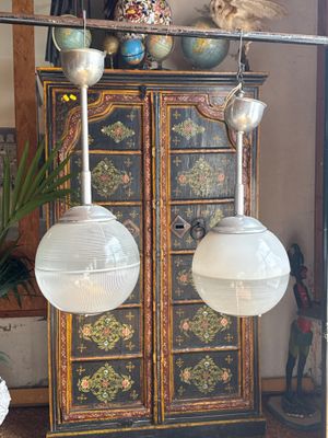 two lamps that are hanging from the ceiling above a cabinet