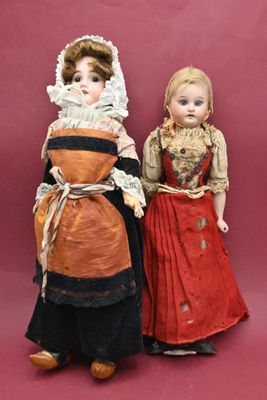 two dolls are standing next to each other on a pink background