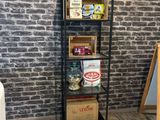 brick wall in the corner of a room with a shelf of food and a chalk board