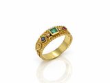 un gros plan d'une bague en or sertie d'émeraudes et de saphirs