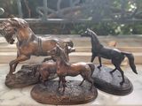trois statues de chevaux en bronze posées sur une table en marbre