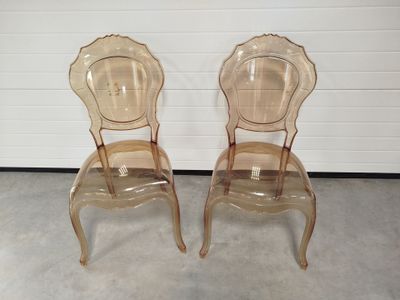 deux chaises transparentes placées côte à côte devant un mur blanc