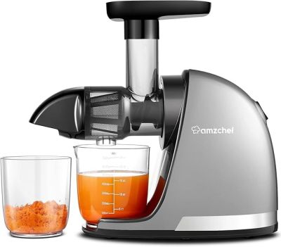 a juicer that is sitting next to a glass of orange juice