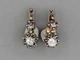 une paire de boucles d'oreilles en diamant et en or posées sur une surface grise