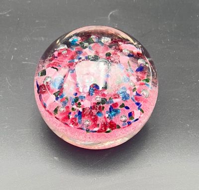 a glass ball with a pink base and colorful sprinkles on it