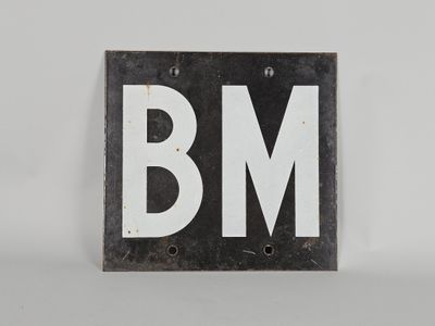 une vieille enseigne en noir et blanc sur laquelle figurent les lettres « bm »