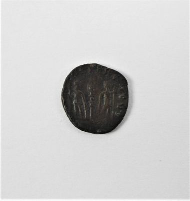 une vieille pièce de monnaie portant une inscription, posée sur une surface blanche