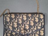 a brown and black purse with a chain on a gray surface