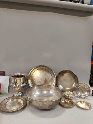 a lot of silver plates and bowls on the counter