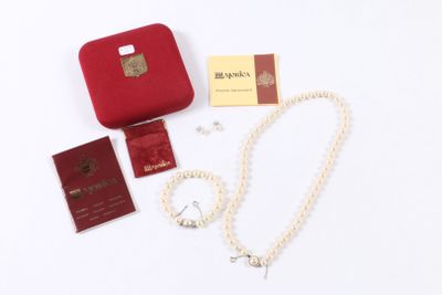 une valise rouge contenant un collier de perles, un passeport et d'autres objets, posée sur une surface blanche