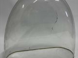 un dôme en verre percé d'un trou, posé sur une surface blanche