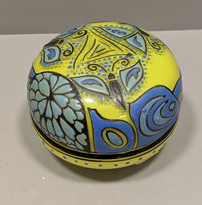 boîte décorative jaune et bleue posée sur une surface blanche