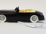a black toy car with a yellow top on a white surface