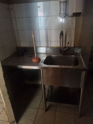 a kitchen with a sink and a trash can in it