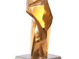 sculpture of a golden sculpture on a silver base on a white surface