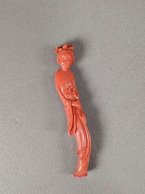 une figurine orange représentant une femme avec un oiseau sur la tête