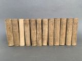 six vieux livres alignés sur une surface grise