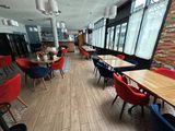 Dans un restaurant aux grandes baies vitrées, des tables et des chaises sont alignées.
