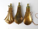 three antique brass bell shaped lamps on a white surface