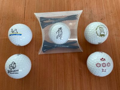 quatre balles de golf dans un sac transparent posé sur une table en bois