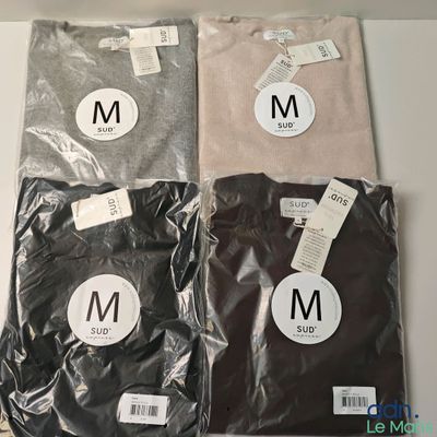 Trois t-shirts portant la lettre « m » sont posés sur une table
