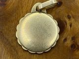 a silver pendant on a wooden surface on a table