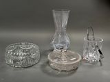 un vase en verre, un bougeoir et un verre posés sur une table