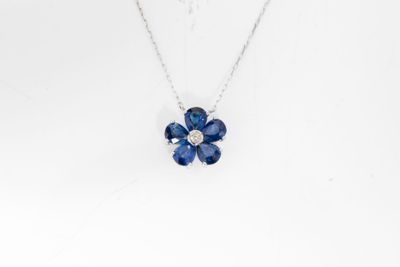 un collier orné d'un pendentif en forme de fleur bleue sur un mannequin blanc