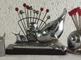 three silver statues of snails and a snail with red flowers