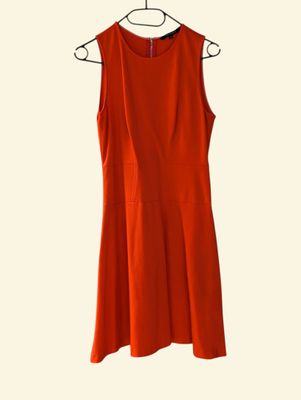 a red dress hanging on a hanger on a white wall