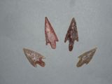 four arrowheads are shown in a row on a gray surface