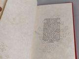 an open book with a hand holding a bookmark in it ' s left hand