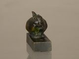 statue of a cat sitting on a block on a table