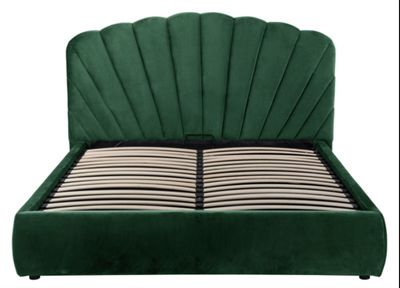 Le cadre de lit est en velours vert et présente un motif festonné.