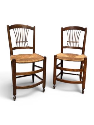 two wooden chairs with wicker seats on wheels against a white background