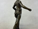 bronze statue of a woman holding a bird on a rock