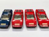 quatre petites voitures sont alignées sur une surface blanche