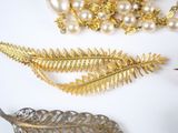a gold leaf brooch and a pearl necklace on a white table