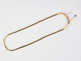a close up of a gold necklace on a white surface