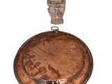 une petite statue représentant un homme debout sur une casserole en métal