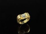 a gold ring with two diamonds on a black surface