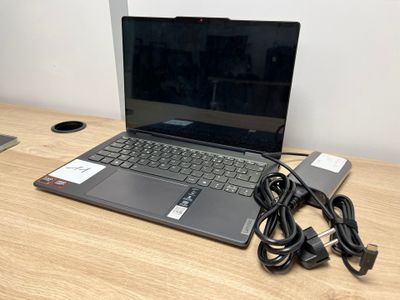 un ordinateur portable posé sur un bureau en bois, avec son chargeur